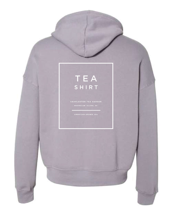 Back view of a soft, storm-colored fleece hoodie featuring a minimalist white tea-themed graphic from Charleston Tea Garden, perfect as a cozy apparel souvenir.