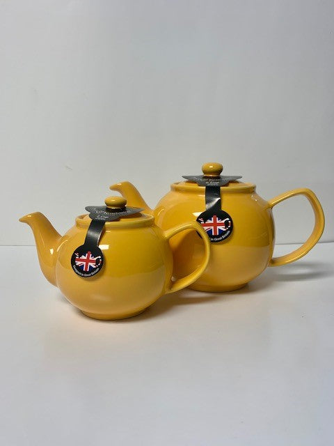 Two bright yellow ceramic teapots in 2 cup and 6 cup sizes, showcasing classic design with round bodies and curved spouts, perfect for a cozy tea experience.