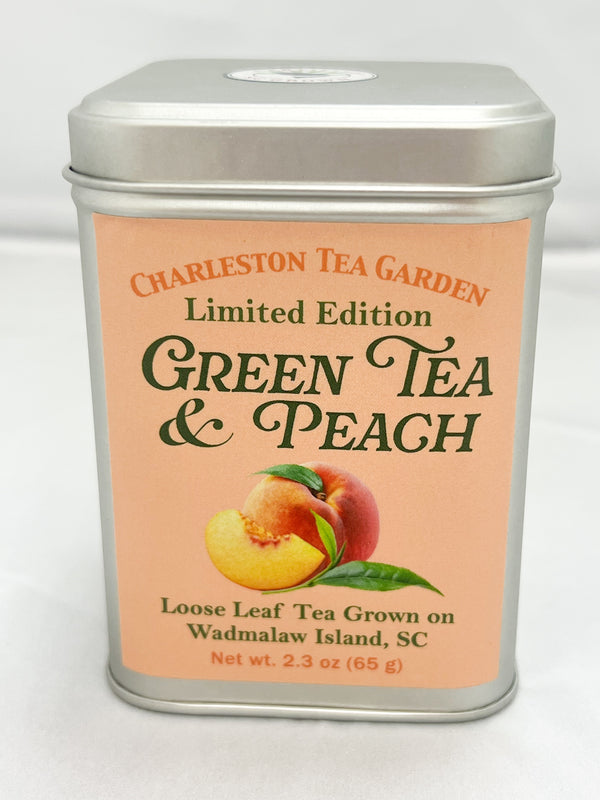 Silver Charleston Tea Garden tin labeled Limited Edition Green Tea and Peach, featuring illustrations of ripe peaches and green leaves on a peach colored label.