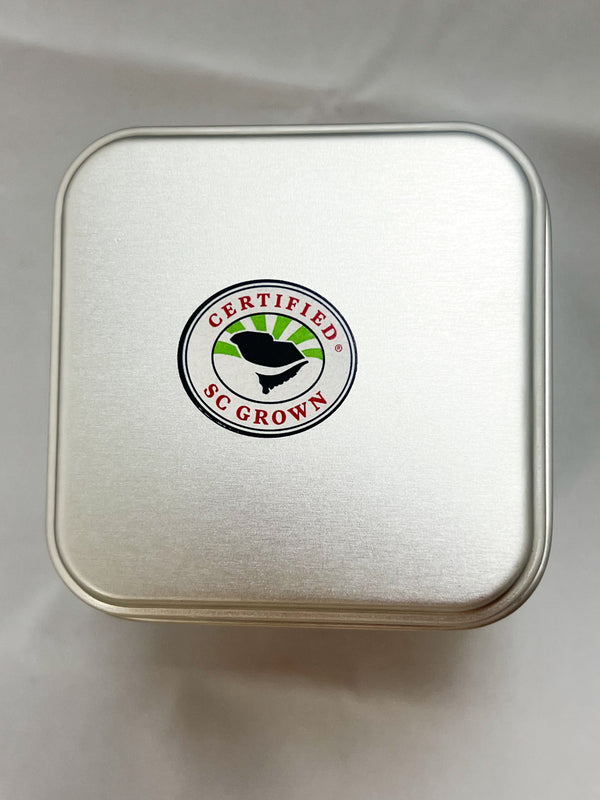 Silver square metal tin with a circular Certified SC Grown seal featuring a black bird over green fields on its lid.