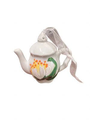 White ceramic teapot ornament with a colorful floral design, curved spout and handle, and a soft mesh ribbon draped over the lid.