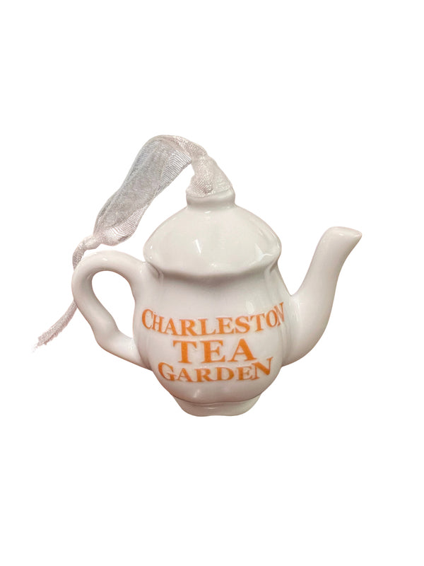 White ceramic teapot ornament with a ribbon loop and orange Charleston Tea Garden lettering on a plain white background