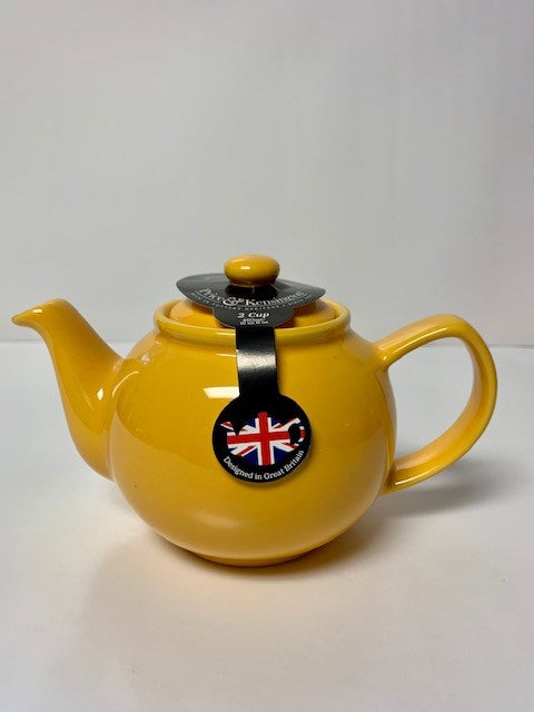 Bright mustard yellow ceramic teapot with a round body and a black tag featuring a British flag, designed for brewing 2 or 6 cups of tea.